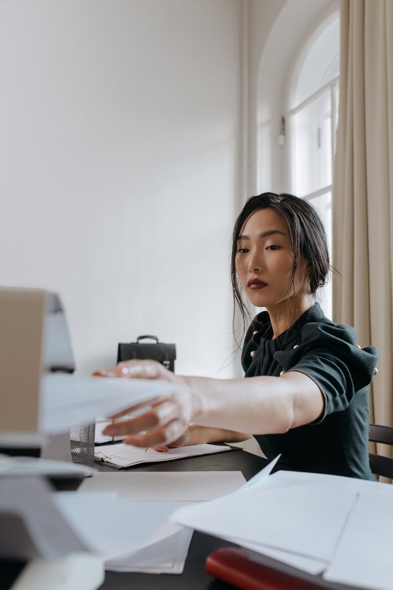 An Asian businesswoman handling paperwork in a modern office setting.